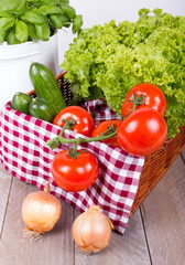 gefüllter Gemüsekorb mit Basilikum auf Holztisch
