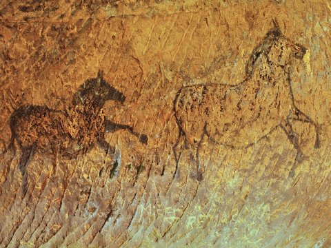 Abstract children art in sandstone cave. Paint of horses on wall