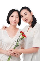 Young woman giving carnation flower to her mother