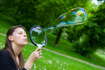 woman inflating colorful soap bubbles in spring park