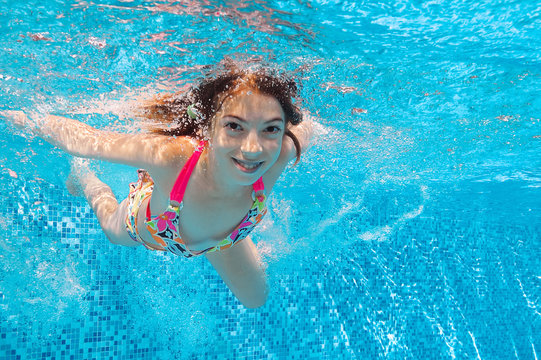 Happy active underwater girl swims in pool and having fun