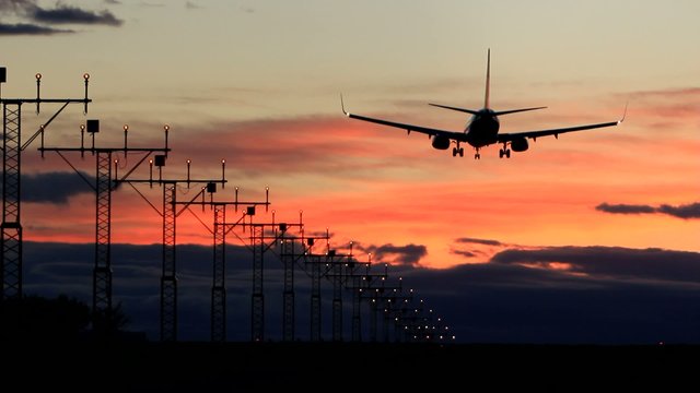 Big jet airplane landing on runway in sunset
