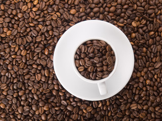 A white cup with many coffee beans on coffe background