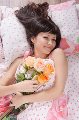 Obraz na płótnie Canvas Beautiful young girl lying in bed with bouquet of roses