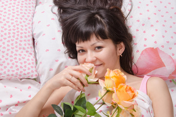 Obraz na płótnie Canvas Beautiful girl lying in bed and enjoy scent of flowers