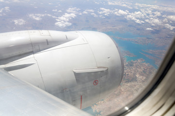 Airplane window with a view of sky and clouds.