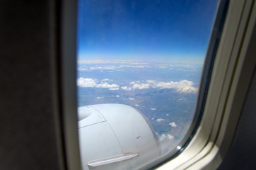 Fototapeta na wymiar Airplane window with a view of sky and clouds.