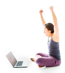 Young man using laptop with arms raised