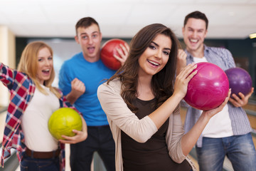 Fototapeta na wymiar Portrait of young woman with friends at bowling alley