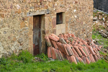 tejas apiladas junto a una casa antigua de piedra © uzkiland