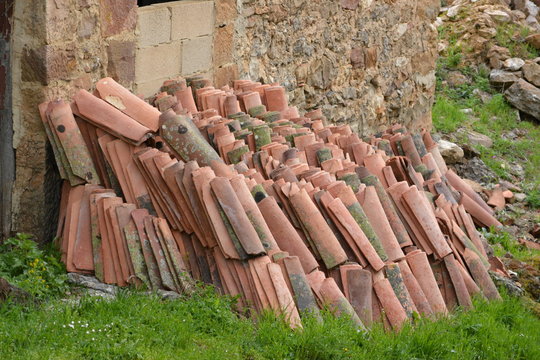 monta&ntilde;a de tejas apiladas en una pared de piedra