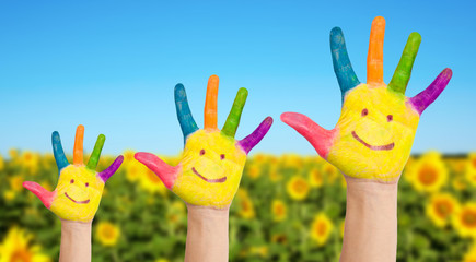 Three painted hands of family on sunflowers field