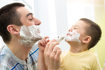 playful father and his son shaving and having fun in bathroom