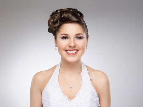 Young and beautiful bride on a grey background