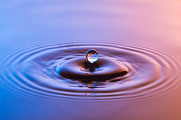 Naklejka na ściany i meble Water drop close up with concentric ripples colourful blue and a