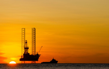 Fototapeta na wymiar Offshore drilling rig and supply vessel at sunset
