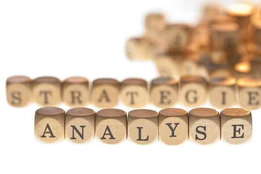 Worte "Strategie" und "Analyse" aus Buchstabenwürfeln, freigestellt, Freisteller, Fokus auf Analyse