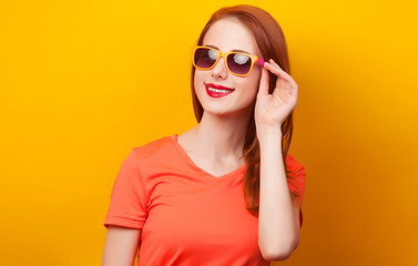 Fototapeta premium Happy redhead girl in sunglasses on yellow background