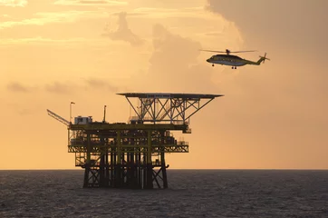 Tuinposter A helicopter transports roughnecks to a rig © corlaffra