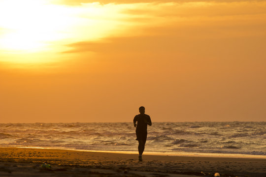 A man running on the beach at sunset