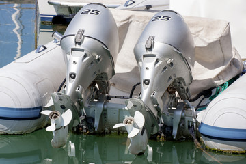 Coppia di motori fuoribordo cromati installati su un'imbarcazione da diporto bianca e blu