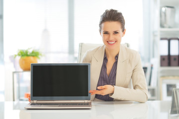 Happy business woman showing laptop blank screen