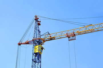 Tall construction tower crane against blue sky
