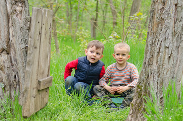 Two cute young boys playing in woodland