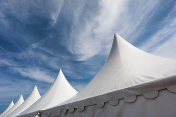 row of white event and party tents against blue sky - 64602295