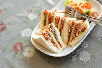 Small pieces Tuna Salad Sandwiches on table .