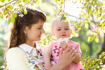 Allergy. Mother and baby blowing nose outdoors