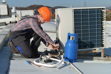 Air Conditioning Repair, young repairman on the roof fixing AC
