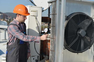 Air Conditioning Repair, young repairman on the roof fixing AC