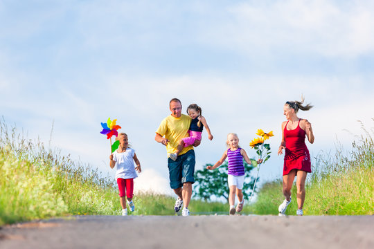 Family with three kids running down a hill in summer