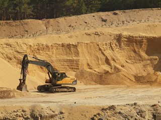 Fototapeta na wymiar Big black orange digger in open sand mine is waiting for driver
