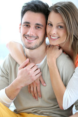 Cheerful couple at home sitting in sofa