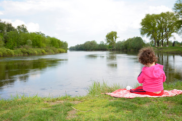 Little girl sitting near the river.