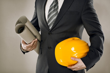 Man architect wearing suit holding blueprint and helmet