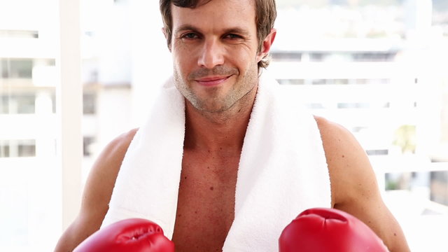 Fit man wearing boxing gloves looking at camera
