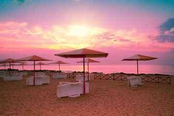 Sunset beach scenery with parasols and sunbeds