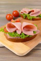 Delicious sandwiches with lettuce and ham on table close-up