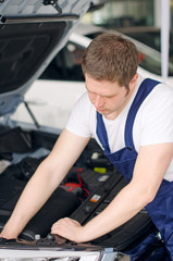 Fototapeta na wymiar Young mechanic repairing car in service center