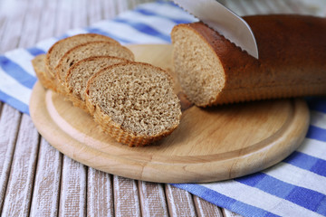 Female hands cutting bread on wooden board, close-up