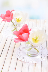 Beautiful tulips in bucket in vase on table on light background
