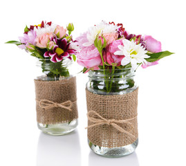 Beautiful bouquet of bright flowers in jars isolated on white