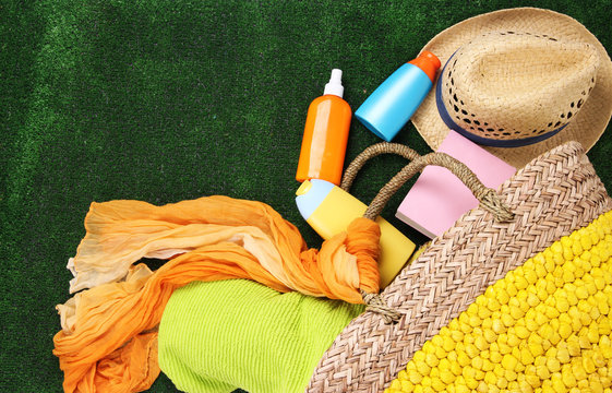 Wicker bag with colorful scarf, towel, bottles of lotions