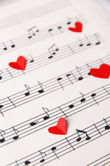 Fototapeta na wymiar Red paper hearts on music book, close-up