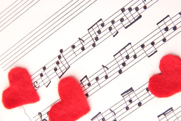 Red paper hearts on music book, close-up, on wooden background