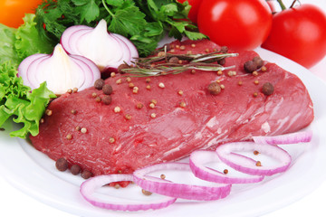 Raw beef meat with vegetables on plate close up