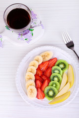 Various sliced fruits on plate on table close-up